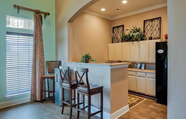 Clubhouse area with fridge, bar stools, counter and window with shades