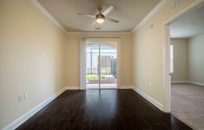 an empty living room with a ceiling fan and a door to a patio
