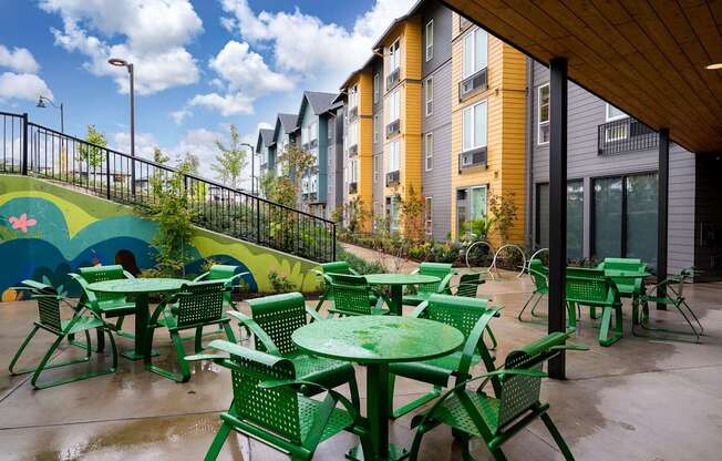 furnished patio with green chairs and tables and a mural