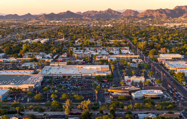 A cityscape with a large parking lot in the foreground and mountains in the background.