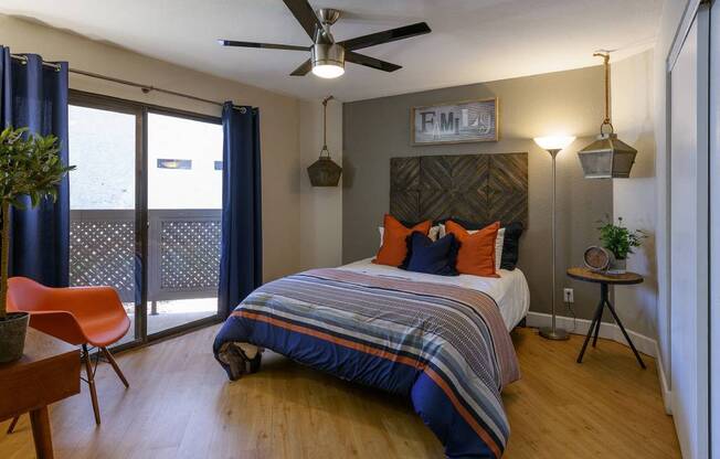 A bedroom with a bed, chair, and ceiling fan.