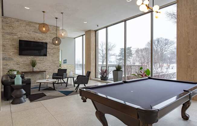 a pool table in the lobby of a building with large windows