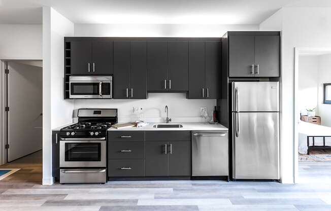 Modern and well-equipped kitchen at L Logan Square Apartments, featuring gray cabinets, sleek countertops, state-of-the-art appliances, and ample storage.