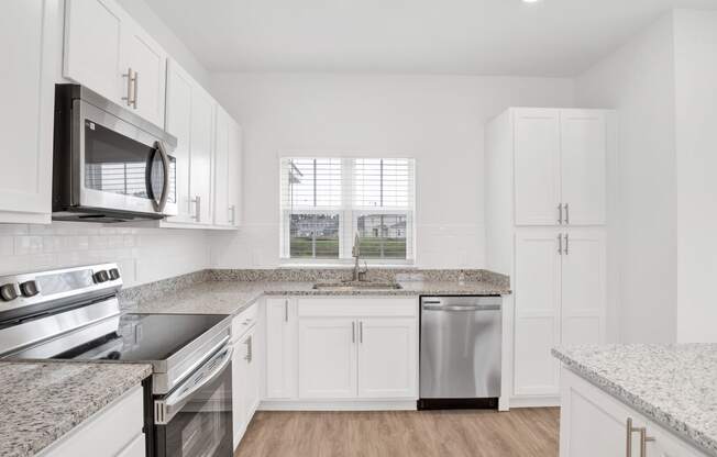 a kitchen with granite counter tops and white cabinets