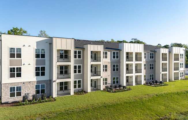 A row of modern apartment buildings with green lawns in front.