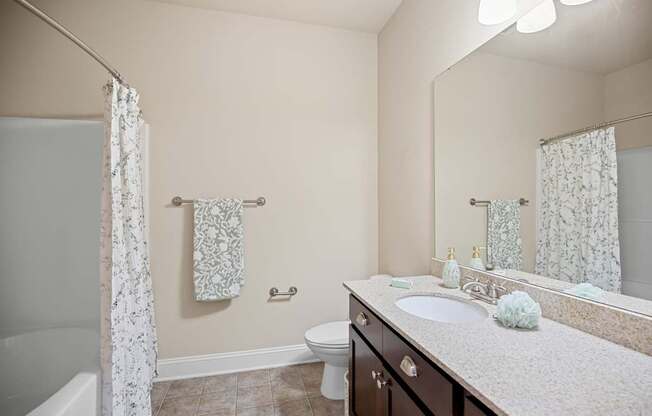 A bathroom with a white sink, toilet, and a bathtub with a white curtain.
