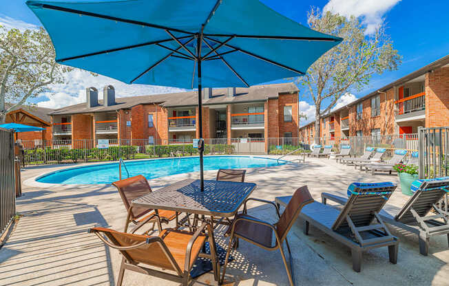 A blue umbrella is over a table with chairs around it.