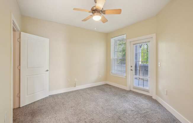 A room with a ceiling fan and carpeted floor.