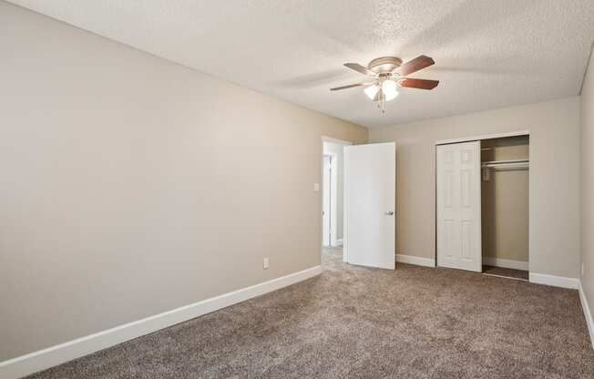 A room with a ceiling fan and carpeted floor.