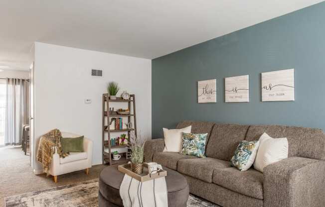Model unit living room with a couch and a chair in front of a blue wall.