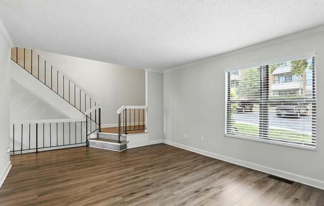 A room with a staircase and a window overlooking a street.