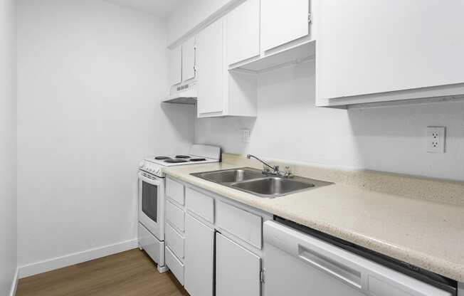 an empty kitchen with white cabinets and a sink