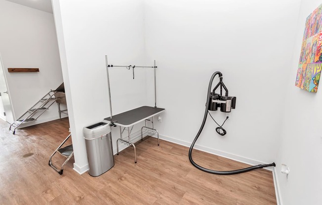 A room with a bench, a trash can, and a hose.