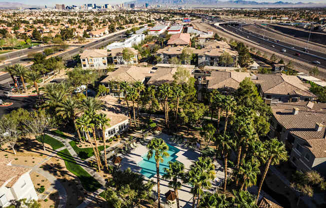 A bird's eye view of a residential area with a swimming pool surrounded by palm trees.