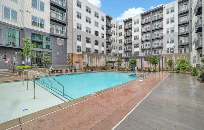 an apartment swimming pool with an apartment building in the background