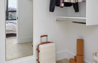 A white suitcase is on the floor next to a wall-mounted closet.