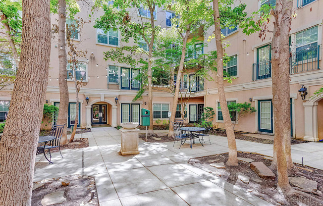A courtyard with a bench and a tree in front of a building.