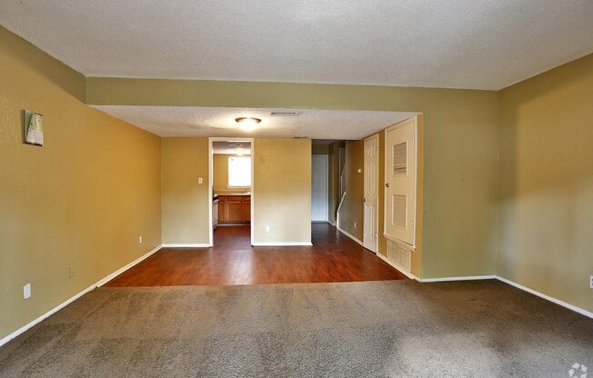 an empty living room with hard wood floors and yellow walls