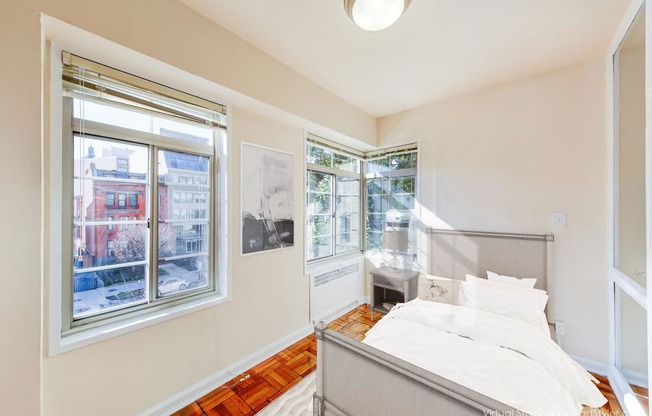 bedroom with bed night stand, hardwood flooring and large windows at baystate apartments washington dc