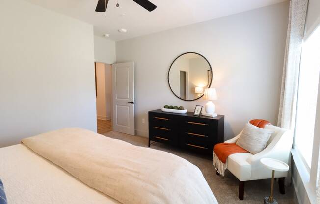 a bedroom with a large bed and a chair and a dresser with a mirror