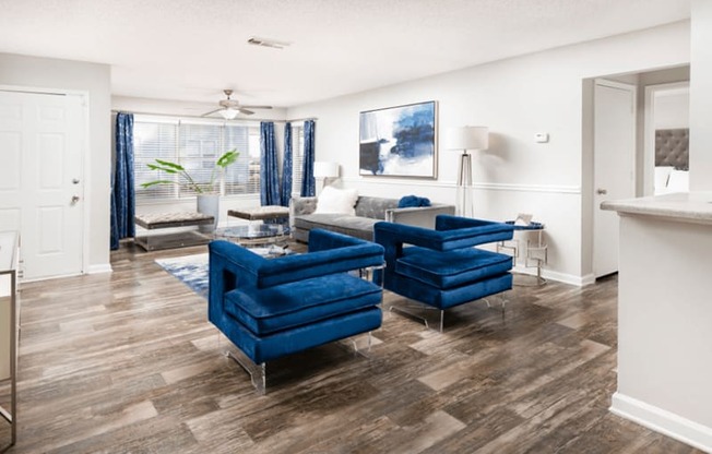 a living room with two blue chairs and a couch