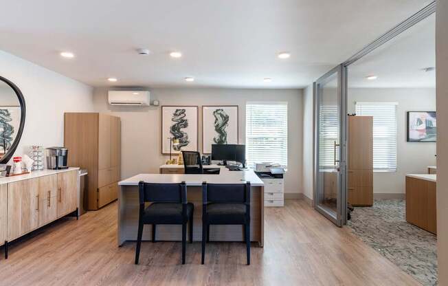 A modern home office with a desk, chairs, and artwork.