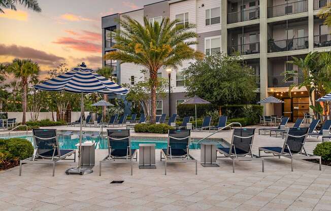 a pool with chairs and umbrellas next to a building