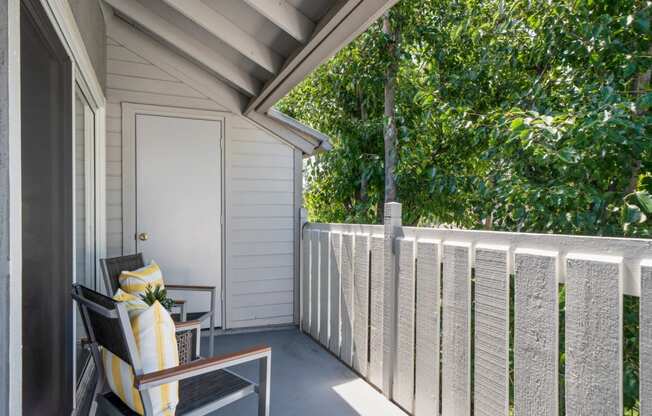 a porch with two chairs and a door to a house