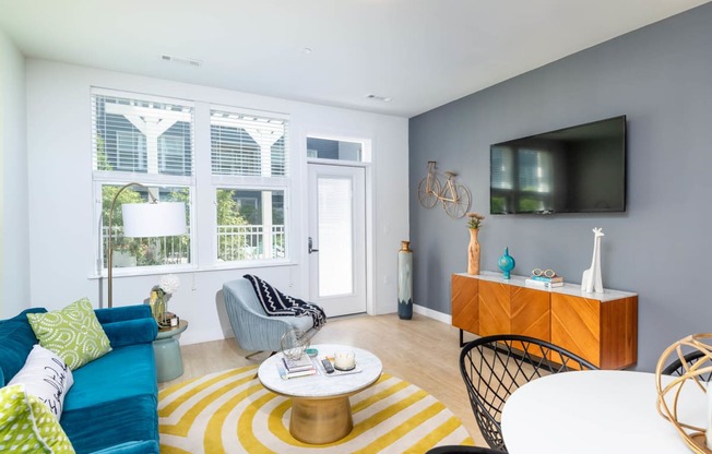 a living room with a blue couch and a yellow and white rug