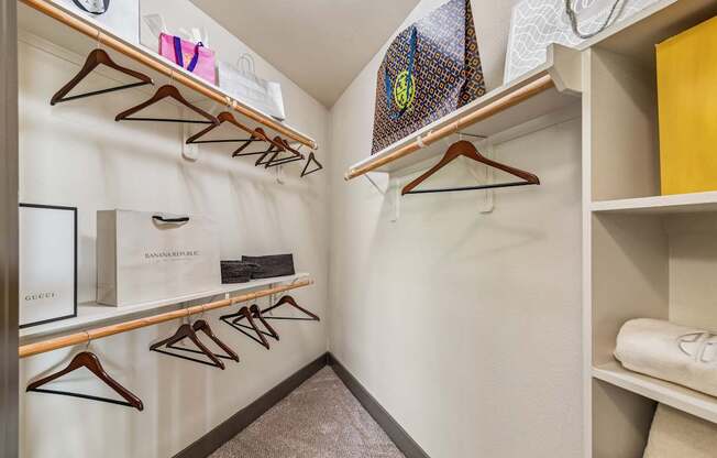 A walk in closet with clothes hanging on hangers.
