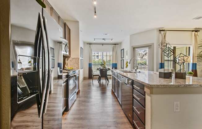 a kitchen with stainless steel appliances and a large island with granite countertops at Alvista Round Rock, Round Rock, Texas