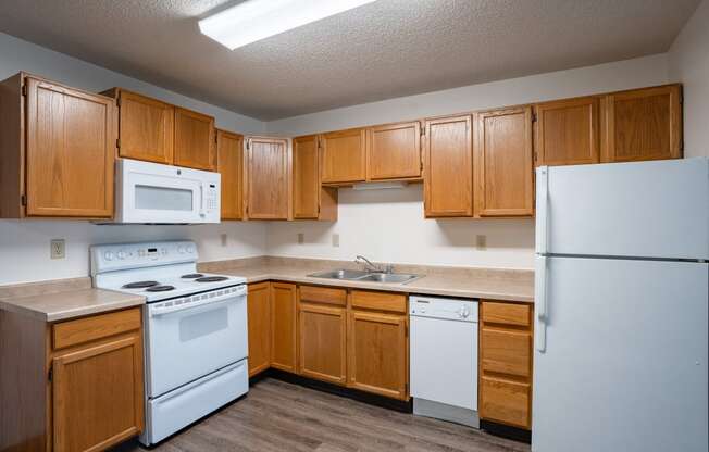 an empty kitchen with white appliances and wooden cabinets