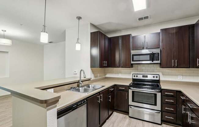 A modern kitchen with dark wood cabinets and stainless steel appliances in the Royal Palm at Oakleaf Plantation Apartments in Jacksonville, FL