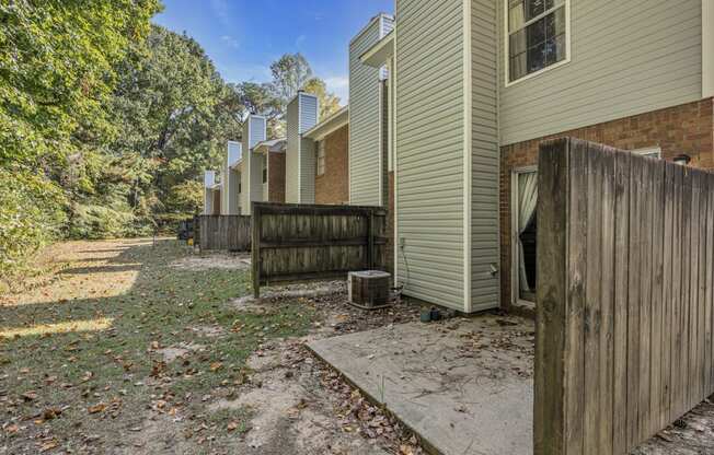 the back yard of a house with a wooden fence and a dirt path