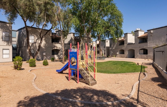 a playground with a swing set and slides in front of a building
