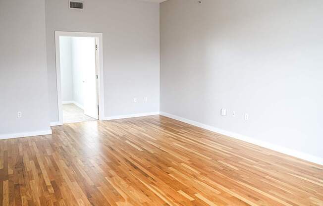 A room with a wooden floor and a doorway leading to another room.
