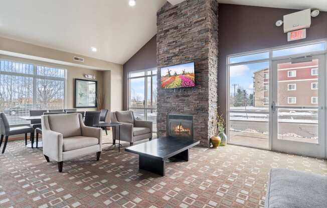 a lobby with couches chairs and a fireplace    and a glass door