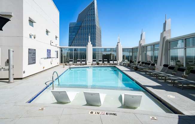 a pool on the rooftop of a building with a skyscraper in the background