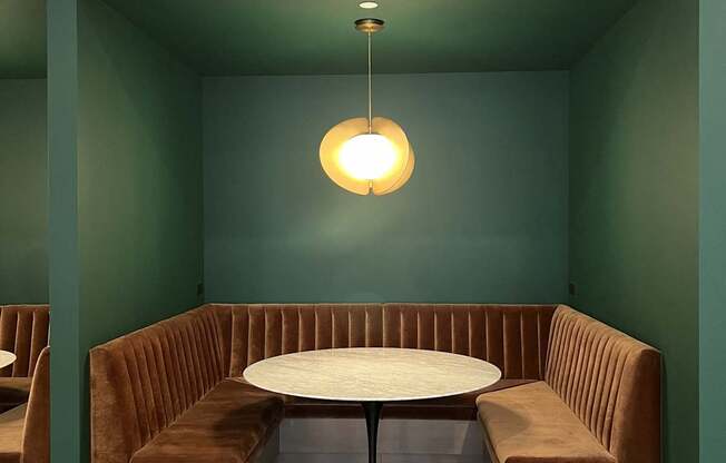 A round table with a white top is surrounded by two brown booths.