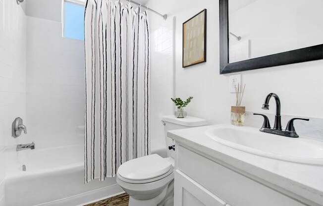 A white bathroom with a toilet, sink, and shower.