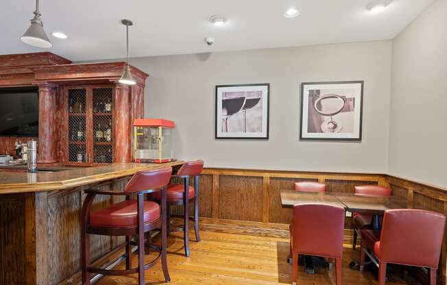 a bar in a restaurant with red chairs