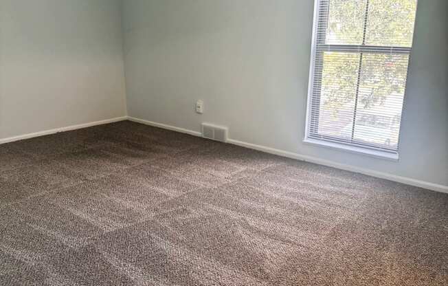 A room with a carpeted floor and a window.