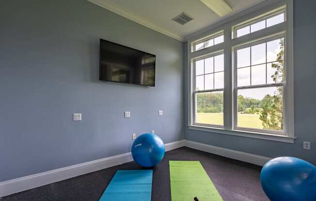a yoga room with a tv and exercise balls