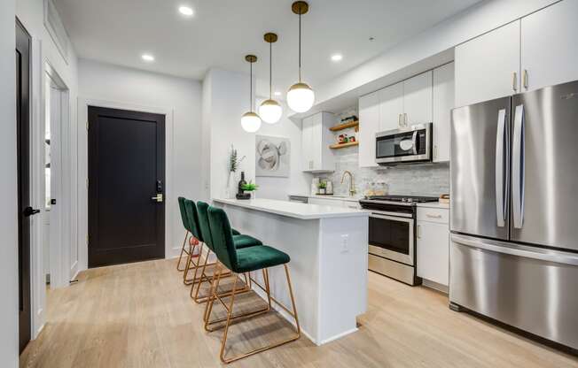 a kitchen with stainless steel appliances and an island with green chairs at Rialto, Washington, 20002