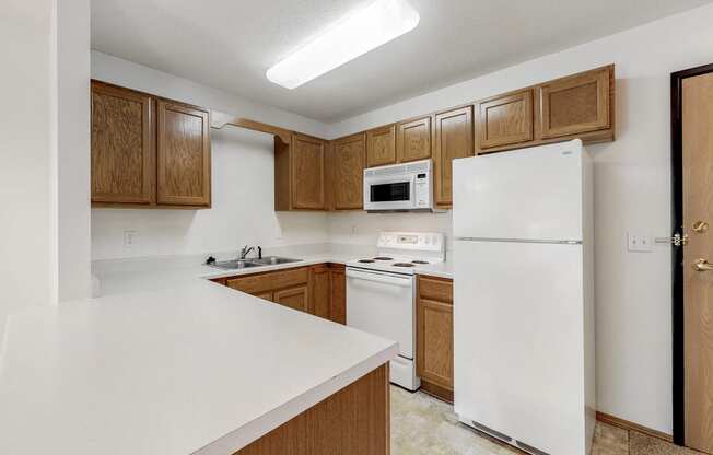 an empty kitchen with white appliances and wooden cabinets