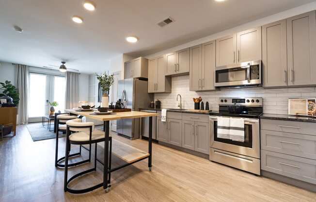 a large kitchen with stainless steel appliances and a wooden table with four chairs