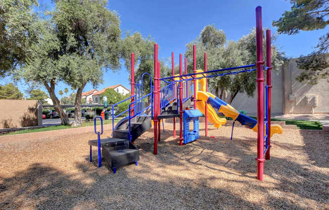 A playground with a yellow slide and red and blue climbing structure.