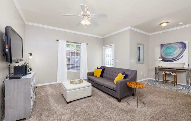 a living room with a gray couch and a white ottoman