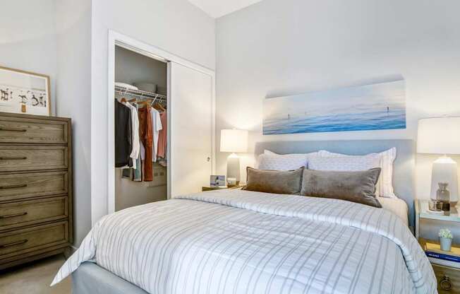 A bedroom with a large bed and a painting on the wall.