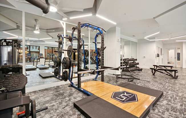 a gym with weights and cardio equipment in a building with white walls at Link Apartments® Calyx, Chapel Hill, 27517